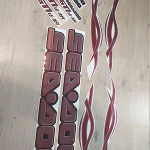 May include: A set of red and silver Sea-Doo decals. The decals include the words "Sea-Doo" and "GTI LE-RFI".