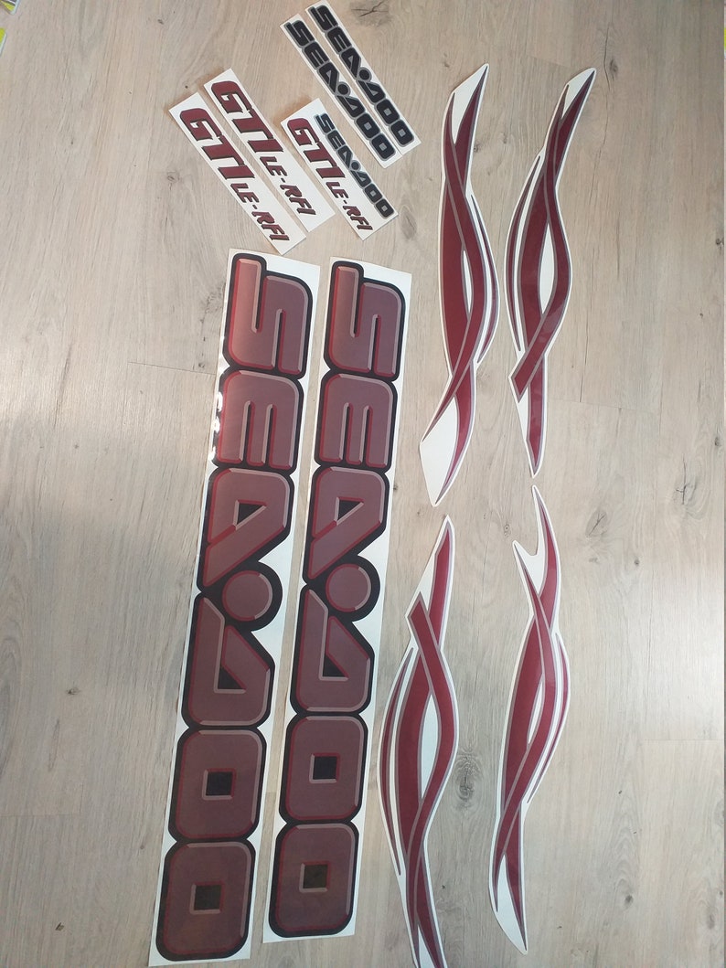 May include: A set of red and silver Sea-Doo decals. The decals include the words "Sea-Doo" and "GTI LE-RFI".
