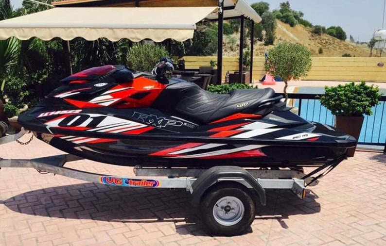 May include: A black and red jet ski with white accents and the text "RXP-X 260" on the side. The jet ski is on a trailer with the text "U.S. Trailer" on the side.