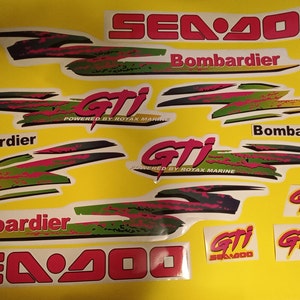 May include: A set of Sea-Doo GTI decals in various colors, including red, pink, green, black, and yellow. The decals feature the Sea-Doo logo, the GTI logo, and the Bombardier logo. The decals are designed for a Sea-Doo GTI personal watercraft.