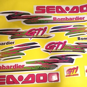 May include: A set of Sea-Doo GTI decals in pink, green, black, and white. The decals feature the Sea-Doo logo, the words "Sea-Doo", "GTI", "Bombardier", and "Powered by Rotax Marine".