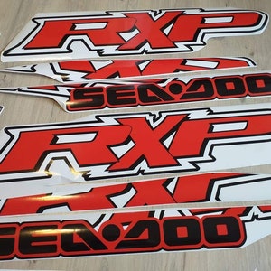 May include: A set of red and black vinyl decals for a Sea-Doo RXP watercraft. The decals feature the words "Sea-Doo" and "RXP" in a bold, stylized font. The decals are designed to be applied to the hull of the watercraft.