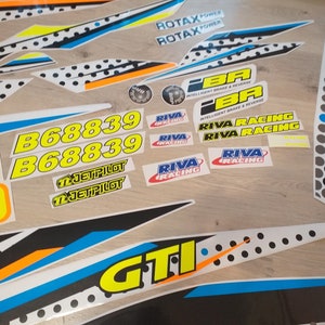 May include: A set of white, black, blue, yellow, and orange stickers with various text and logos, including "ROTAX POWER", "RIVA RACING", "B68839", "JETPILOT", and "GTI".