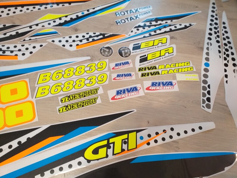 May include: A set of white, black, blue, yellow, and orange stickers with various text and logos, including "ROTAX POWER", "RIVA RACING", "B68839", "JETPILOT", and "GTI".