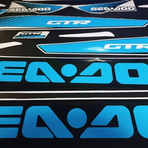May include: Close-up of two blue and black Sea-Doo decals with the text "Sea-Doo" and "Sea-Doo 200" in white.