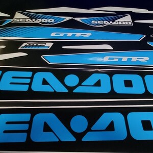 May include: A set of blue and black Sea-Doo decals featuring the text "Sea-Doo", "GTR", and "ROTAX" in white. The decals are designed for a watercraft.