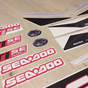 May include: A set of red and white Sea-Doo decals with the text "Sea-Doo", "GTI", "130", and "SE". There are also black and white decals with the text "ROTAX 4-TEC" and "CLOSED-LOOP COOLING".