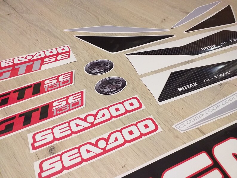 May include: A set of red and white Sea-Doo decals with the text "Sea-Doo", "GTI", "130", and "SE". There are also black and white decals with the text "ROTAX 4-TEC" and "CLOSED-LOOP COOLING".