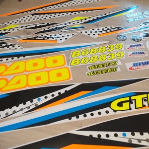 May include: A set of black, white, blue, orange and yellow motorcycle decals with the text "A200", "B68839", "JETPILOT", "RIVA RACING", "ROTAX", and "GTI".