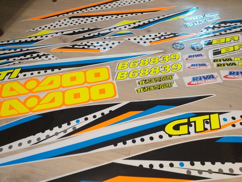 May include: A set of black, white, blue, orange and yellow motorcycle decals with the text "A200", "B68839", "JETPILOT", "RIVA RACING", "ROTAX", and "GTI".