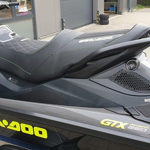 May include: A black and gray Sea-Doo GTX 260 jet ski with yellow and green accents. The jet ski has a black seat with a quilted pattern and a black handlebar. The jet ski is on a trailer.