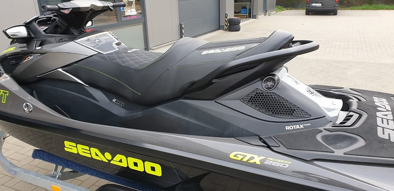 May include: A black and gray Sea-Doo GTX 260 jet ski with yellow and green accents. The jet ski has a black seat with a quilted pattern and a black handlebar. The jet ski is on a trailer.