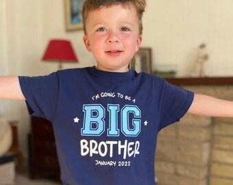 May include: A young boy wearing a navy blue t-shirt with the text "I'm going to be a BIG BROTHER January 2022" in white and blue lettering.