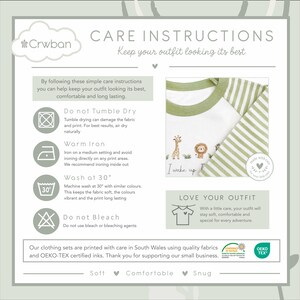 May include: A care instructions graphic featuring a white and green striped long-sleeve top. The top has a green collar and a design with a giraffe, lion, and the words "I wake up". Washing instructions are also included.
