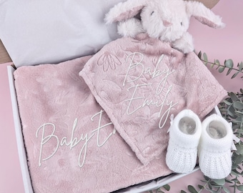 Peut inclure: Un coffret cadeau pour bébé dans une boîte blanche, comprenant une couverture rose et une couverture de sécurité assortie avec une broderie florale et le nom "Baby Emily". Comprend un lapin en peluche blanc et une paire de chaussons blancs.