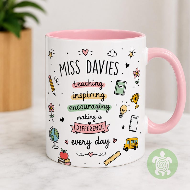 May include: A white ceramic mug with a light pink interior and handle. The exterior features the text MISS DAVIES followed by teaching, inspiring, encouraging, making a DIFFERENCE, every day, surrounded by colorful school-themed icons.