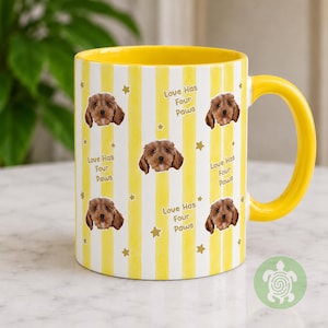 May include: A yellow and white striped ceramic mug featuring a repeating pattern of a brown puppy face, small gold stars, and the text Love Has Four Paws. The mug has a solid yellow interior and a matching yellow handle on the right side.