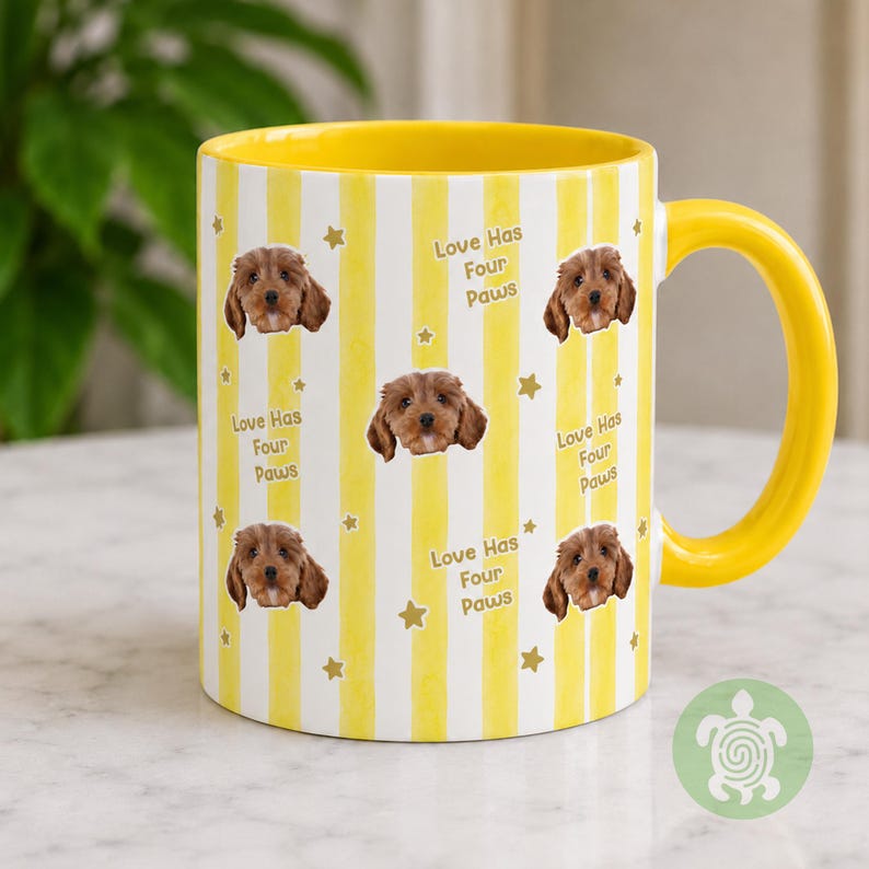 May include: A yellow and white striped ceramic mug featuring a repeating pattern of a brown puppy face, small gold stars, and the text Love Has Four Paws. The mug has a solid yellow interior and a matching yellow handle on the right side.