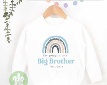 May include: White long-sleeve sweatshirt with a rainbow design and the text "I'm going to be a Big Brother Est. 2025".