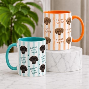 May include: Two ceramic mugs featuring dog portraits and text. One mug has a teal handle and interior with a teal striped pattern and the text "Forever in My Heart." The other mug has an orange handle and interior with an orange striped pattern and the text "I Love My Dog."