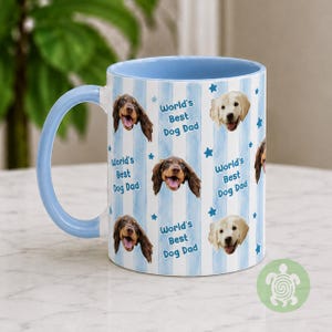 May include: A ceramic mug with a light blue handle and interior, featuring a repeating pattern of light blue vertical stripes, small blue stars, and the text World's Best Dog Dad alongside photographic portraits of brown and cream-colored dogs.