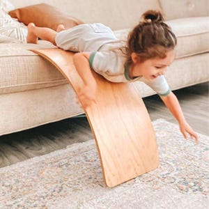 Preschooler leaning forward on a wobble board, building stability and coordination through kid pretend play.