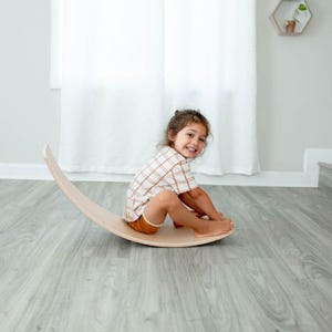 Kid rocking back and forth on a wobble board, improving balance, focus, and active play engagement.