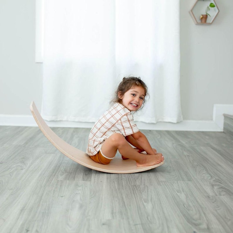Kid rocking back and forth on a wobble board, improving balance, focus, and active play engagement.