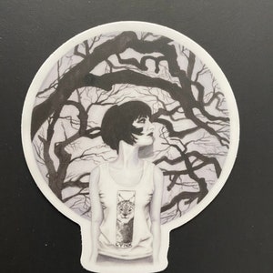 Peut inclure: Autocollant noir et blanc représentant une femme portant un débardeur avec un motif de lynx. La femme est devant un arrière-plan de branches d'arbres dénudées. Le mot "LYNX" est imprimé sur le débardeur.