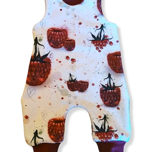 Könnte beinhalten: Weiße Baby-Latzhosen mit Himbeer-Druck. Die Latzhosen haben einen dunkelroten Saum und sind ärmellos.