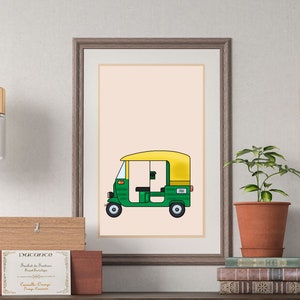 May include: A framed illustration of a green and yellow auto rickshaw, also known as a tuk-tuk, on a light pink background. The illustration is hanging on a wall above a wooden table with two drawers.