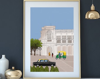 May include: An art print featuring a detailed illustration of a building facade, a black car, and a yellow and green auto rickshaw. The artwork is framed in gold and displayed on a white and gold table. A gold pendant light hangs above.