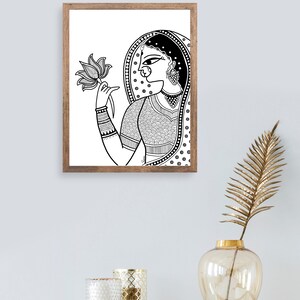 May include: Black and white line art print of a woman in traditional Indian clothing holding a lotus flower. The woman is wearing a veil and jewelry. The print is framed in a wooden frame.