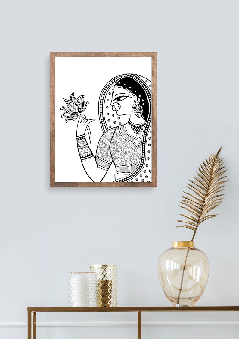 May include: Black and white line art print of a woman in traditional Indian clothing holding a lotus flower. The woman is wearing a veil and jewelry. The print is framed in a wooden frame.