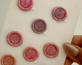 May include: A collection of rose-shaped wax seals in shades of pink, peach, and purple. The seals are arranged on a white card with the text "Handmade in Canada" and "Bay & Harbour".