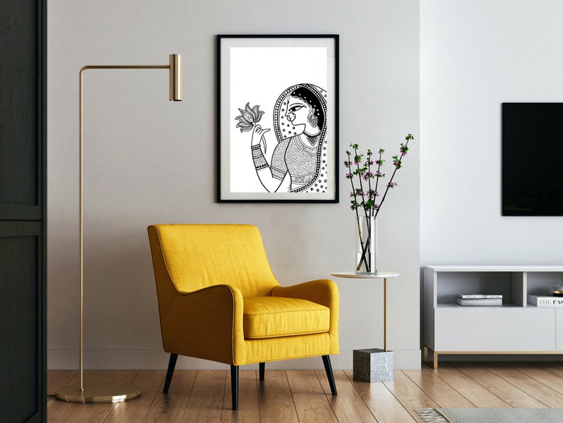 May include: Black and white line art print of a woman holding a lotus flower. The print is framed in a black frame and hanging on a white wall.