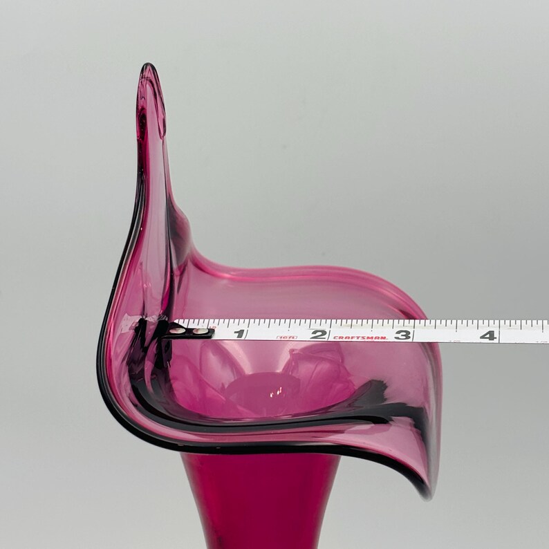 Puede incluir: Un jarr&oacute;n de vidrio rosa oscuro con una abertura ancha y acampanada y un cuello estrecho. El jarr&oacute;n tiene aproximadamente 7,6 cm de ancho en la abertura.