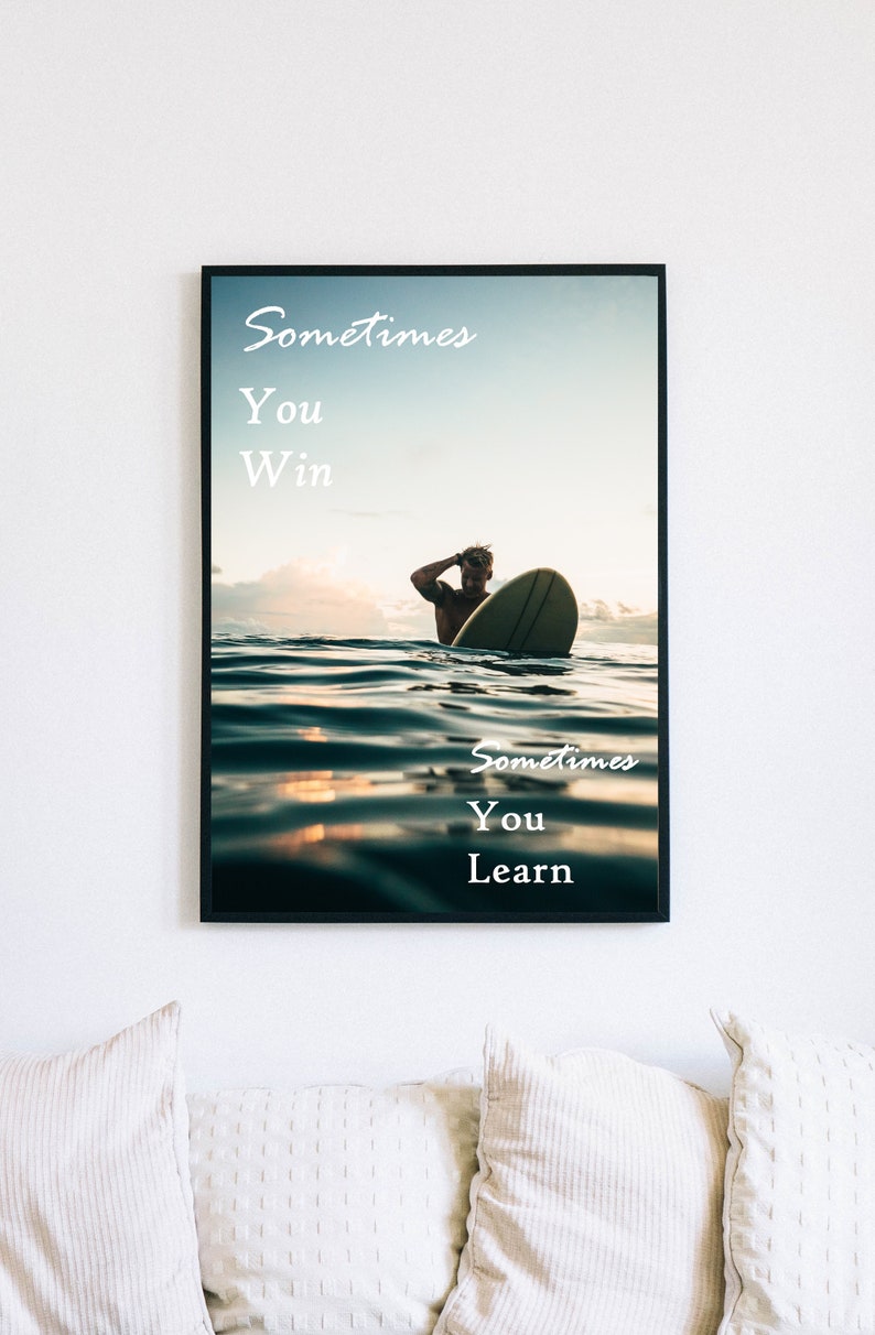 K&ouml;nnte beinhalten: Ein Motivationsposter mit einem Surfer, der bei Sonnenuntergang auf einer Welle reitet. Das Poster zeigt den Text "Sometimes you win. Sometimes you learn."