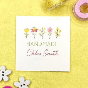 Puede incluir: Una etiqueta blanca con una fila de cinco flores de colores, el texto "HANDMADE" en verde y el nombre "Chloe Smith" en rosa.
