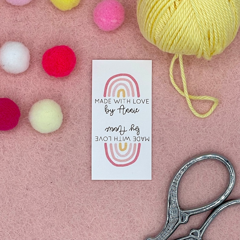 May include: A white tag with a pink and gold rainbow design. The text on the tag reads "MADE WITH LOVE by Annie".