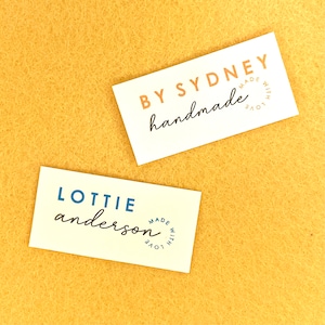 May include: Two white business cards with blue and orange text. The top card says "By Sydney handmade made with love". The bottom card says "Lottie anderson made with love".