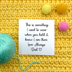 May include: A white card with black text that reads "This is something I used to wear when you hold it, know I am there. Love Always Dad" with a heart symbol.