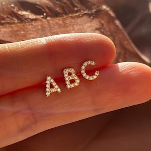 May include: Three gold initial earrings with diamond accents. The letters are A, B, and C.