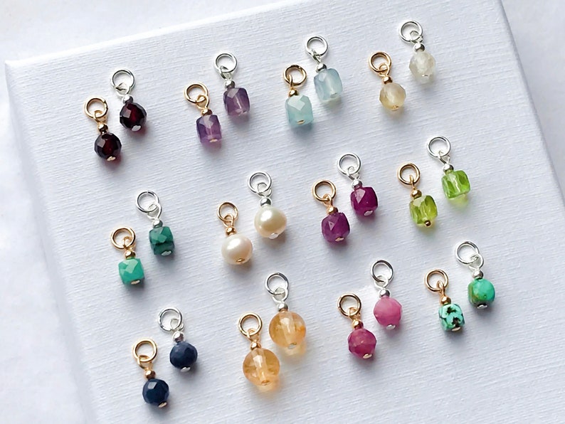May include: A collection of 10 pairs of gemstone charms, each pair featuring a different color and type of gemstone. The charms are made of silver and gold and are perfect for adding a touch of sparkle to jewelry.