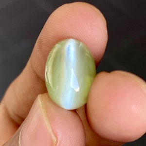 May include: A light green oval-shaped gemstone with a blue-white iridescent sheen.