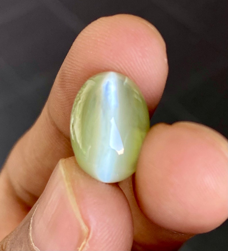 May include: A light green oval-shaped gemstone with a blue-white iridescent sheen.
