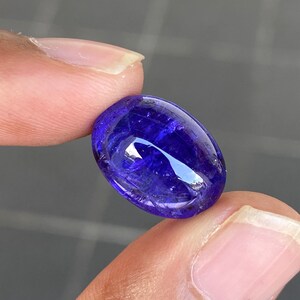 May include: A deep blue oval-shaped gemstone with a smooth, polished surface. The stone has a slight shimmer and a hint of purple.