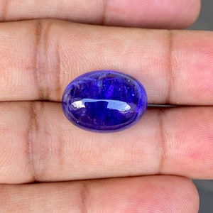 May include: A deep blue oval-shaped gemstone with a smooth, polished surface.