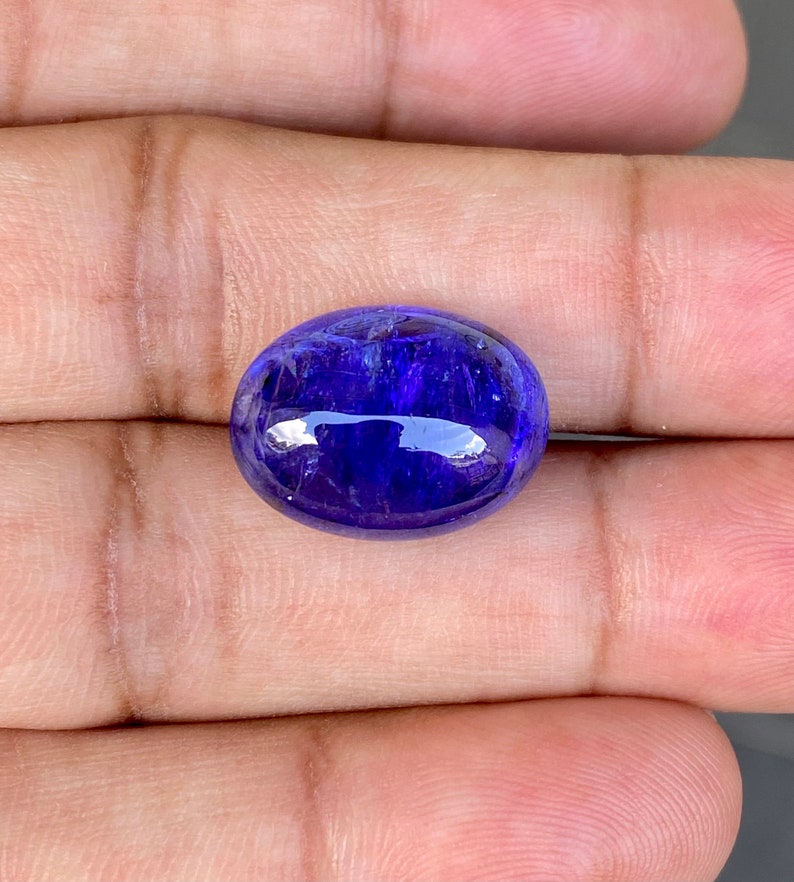 May include: A deep blue oval-shaped gemstone with a smooth, polished surface.