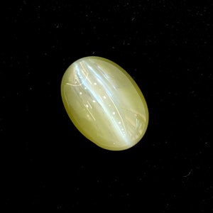 May include: A light green oval-shaped gemstone with a shimmering, iridescent effect.